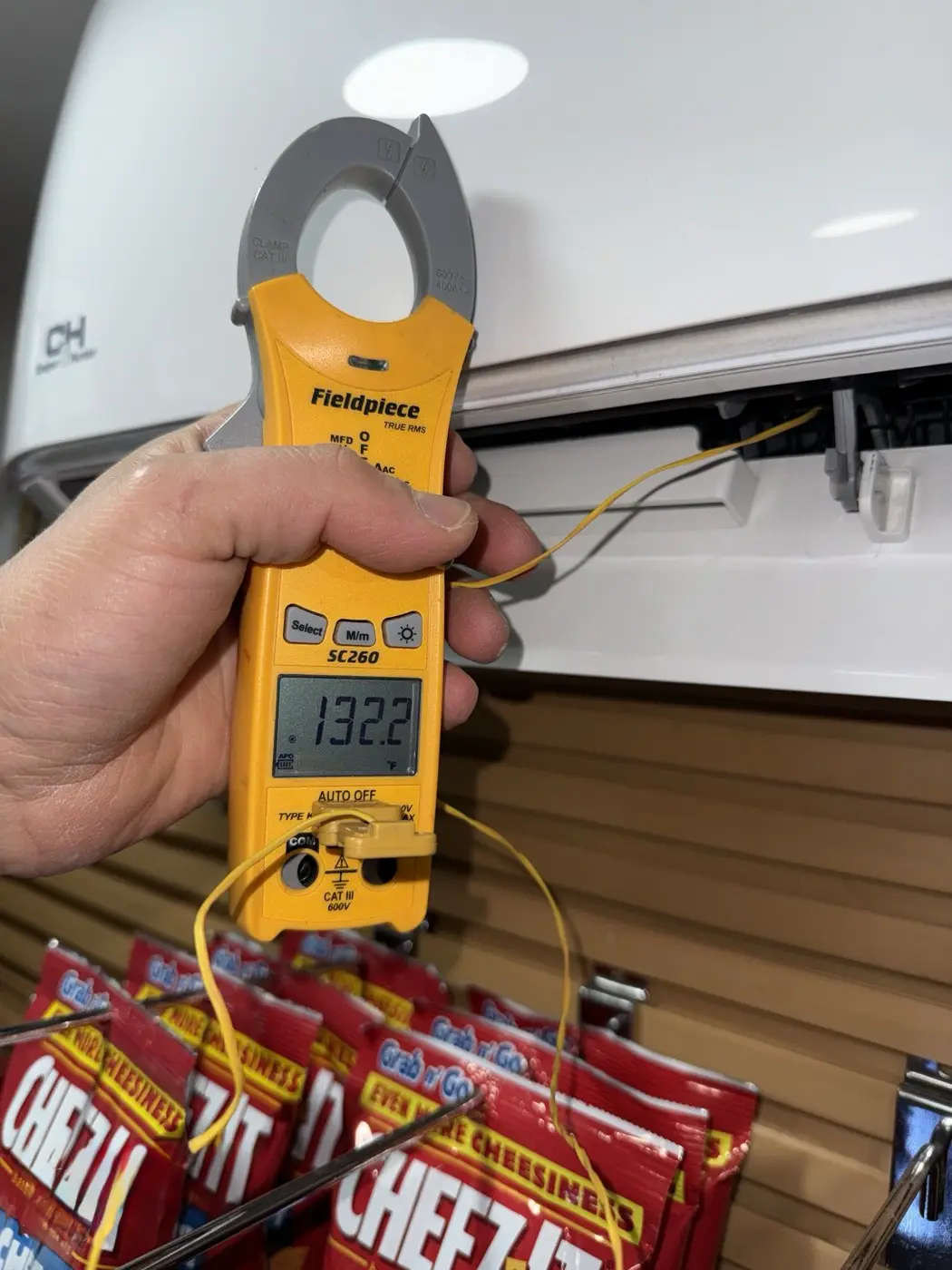 Technician measuring supply-air temperature on a Cooper&Hunter wall-mounted mini-split
