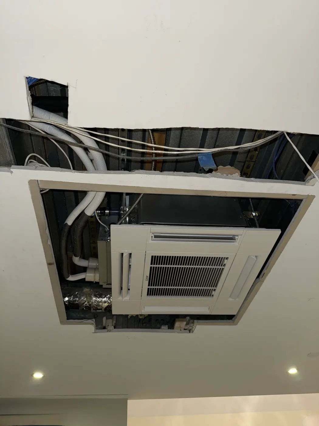 Ceiling-cassette indoor unit being fitted into the ceiling during installation